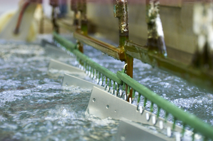 Perforated barrel drum rinsing over metal finishing tanks
