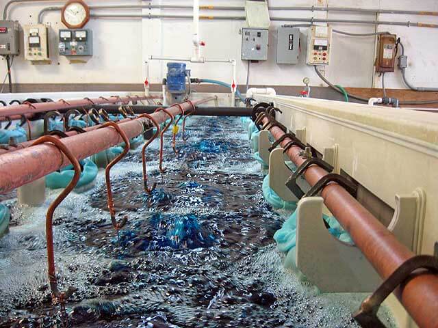 Copper plating line with rack-loaded parts in an agitated treatment bath